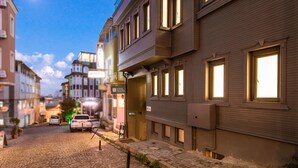 Ein Gebäude mit mehreren Fenstern und einer Tür, eine gepflasterte Straße und ein geparktes Auto.