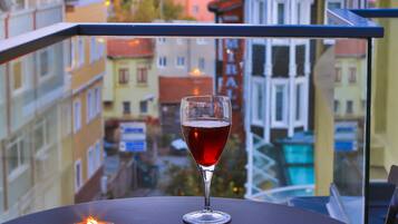 Un balcón con una mesa, una vela y una copa de vino tinto.