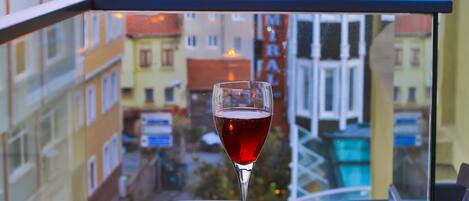 A balcony with a table, a candle, and a glass of red wine.