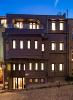 Ein mehrstöckiges Gebäude mit Eingangsbereich, zahlreichen Fenstern und einem sichtbaren Schild, das ein Hotel anzeigt.