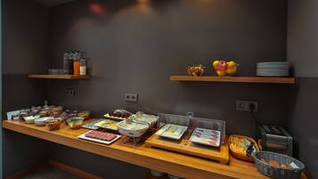 Een buffetopstelling met diverse gerechten en dranken op een houten toonbank.
