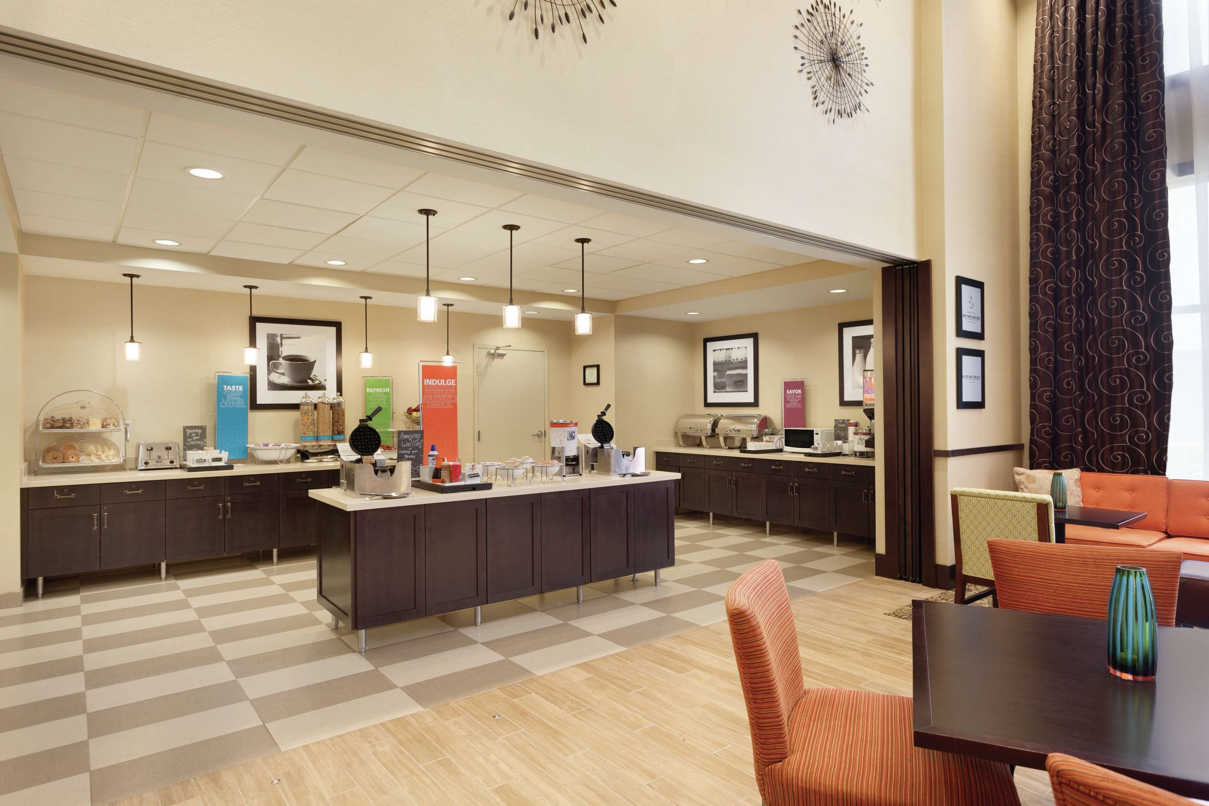 Un vestíbulo de hotel moderno con piso a cuadros, una recepción central con diversos servicios y zonas de estar.