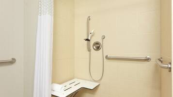 A shower area with a grab bar, a handheld showerhead, and a seat.