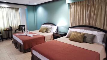 A hotel room with two beds, a small table, and a chair.