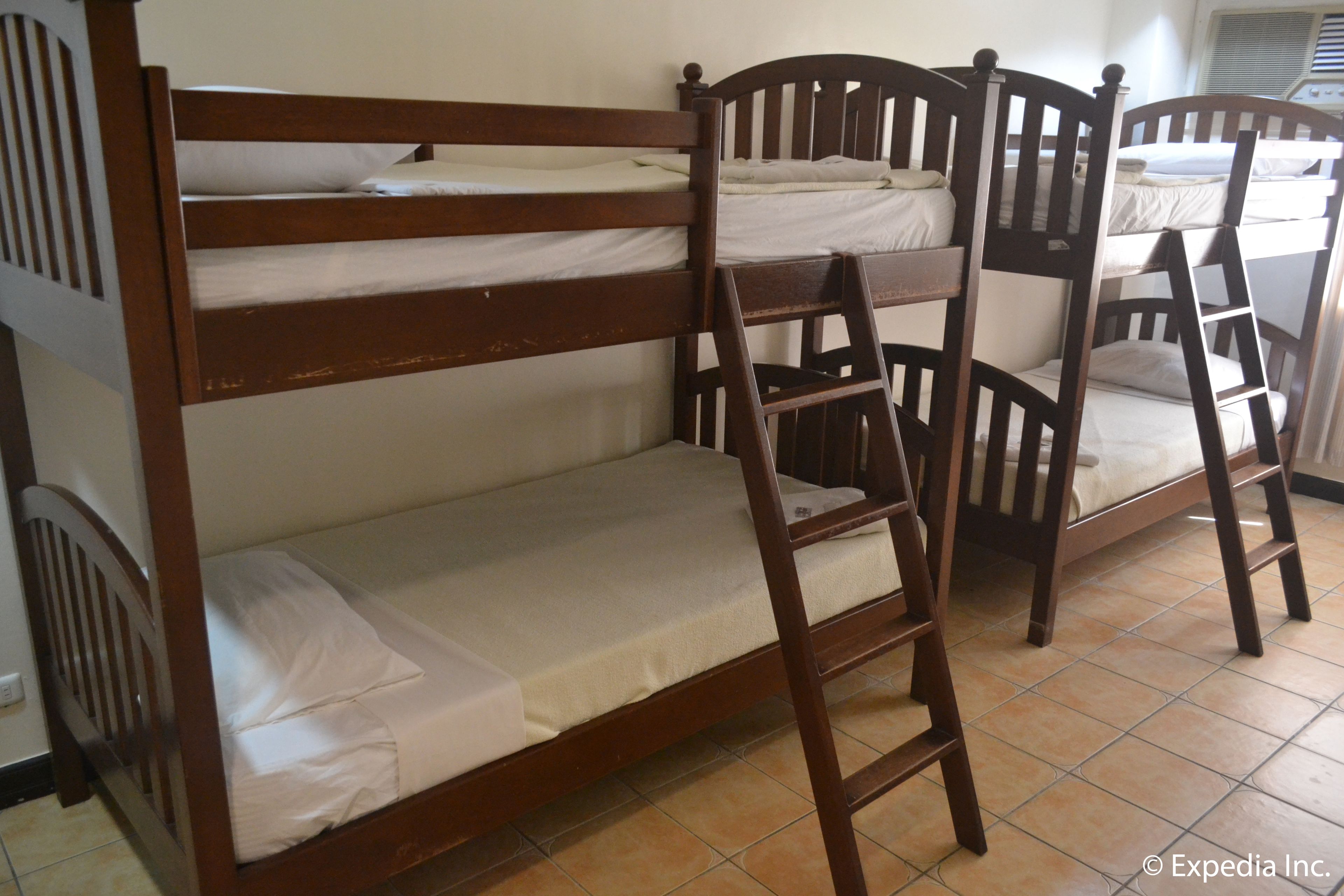 A bunk bed with a ladder, wooden headboard, and white bedding.