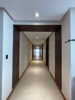 A long, narrow hallway with a wooden frame on the sides, a tiled floor, and a ceiling with recessed lighting.
