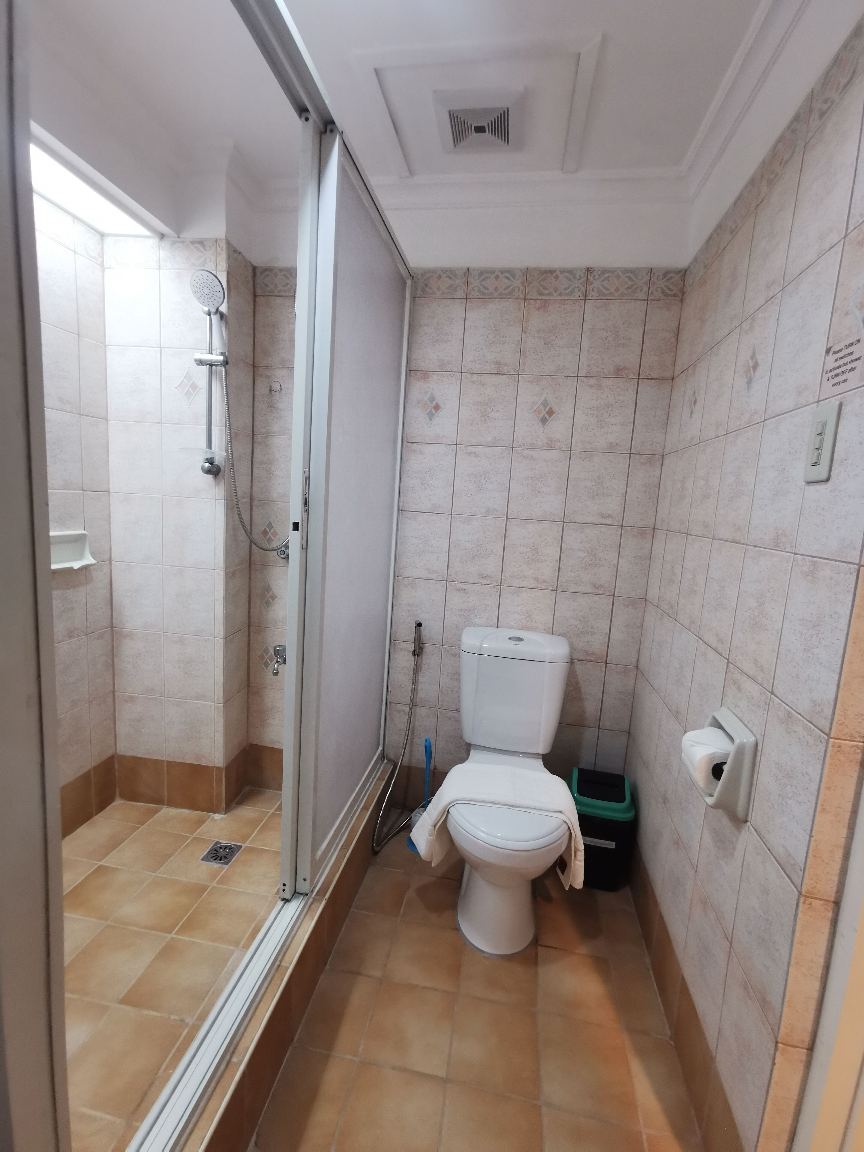 Une salle de bain équipée d’une douche, de toilettes et d’un sèche-mains.
