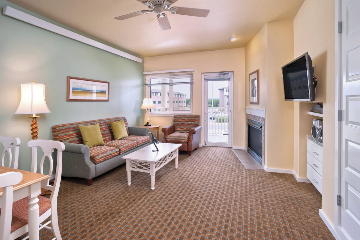 A living room with a sofa, chairs, a coffee table, a television, and a fireplace.