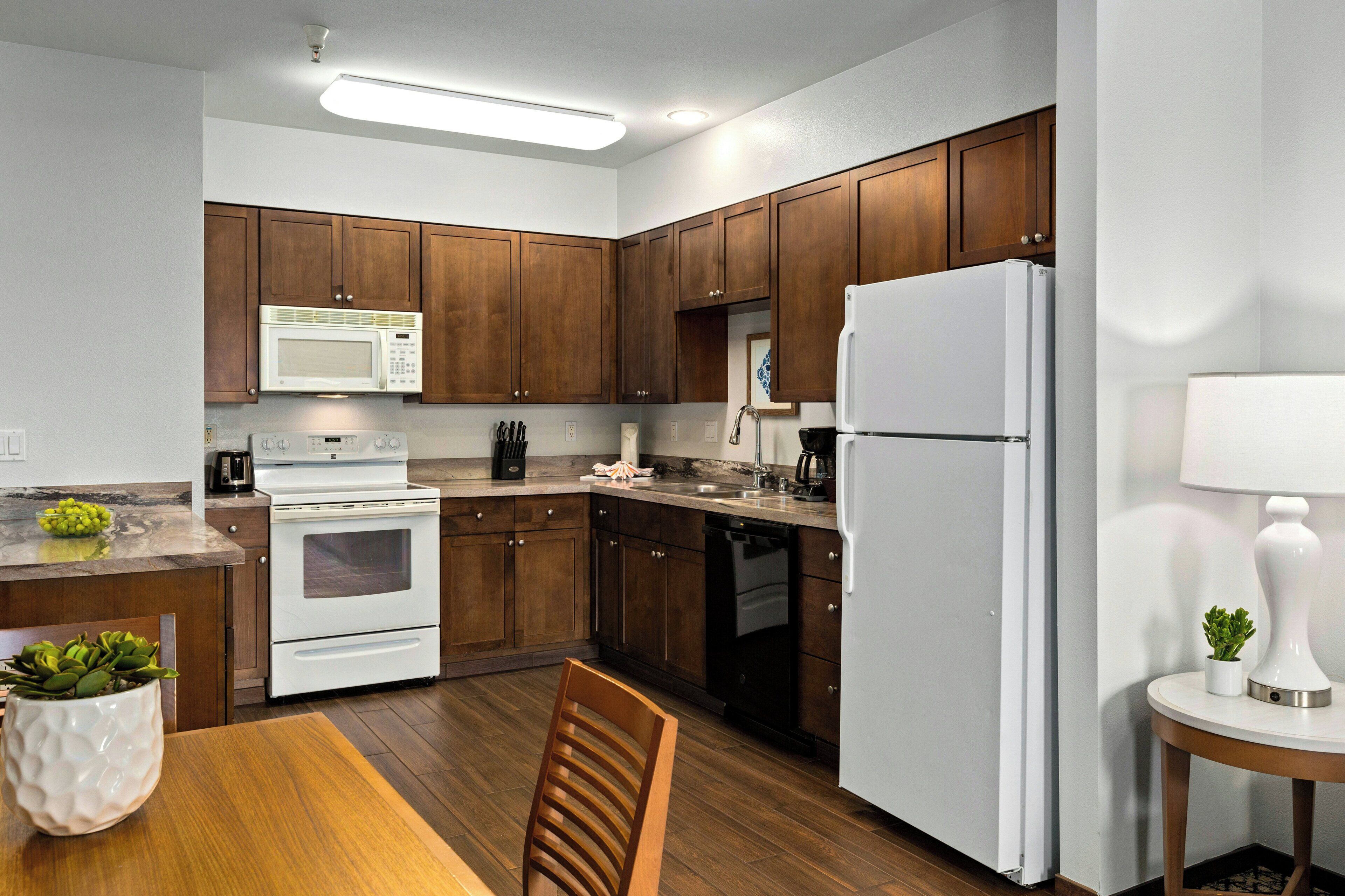 A modern kitchen with wooden cabinets, a white refrigerator, a microwave, and a stove.