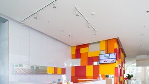 A modern reception desk with a colorful wall design and a flat-screen TV. -  Ayda Mangga Dua d/h Zuri Express Mangga Dua (Jakarta)