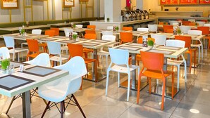 A modern restaurant interior with multiple dining tables and chairs, pendant lighting, and menu boards on the walls. -  Ayda Mangga Dua d/h Zuri Express Mangga Dua (Jakarta)