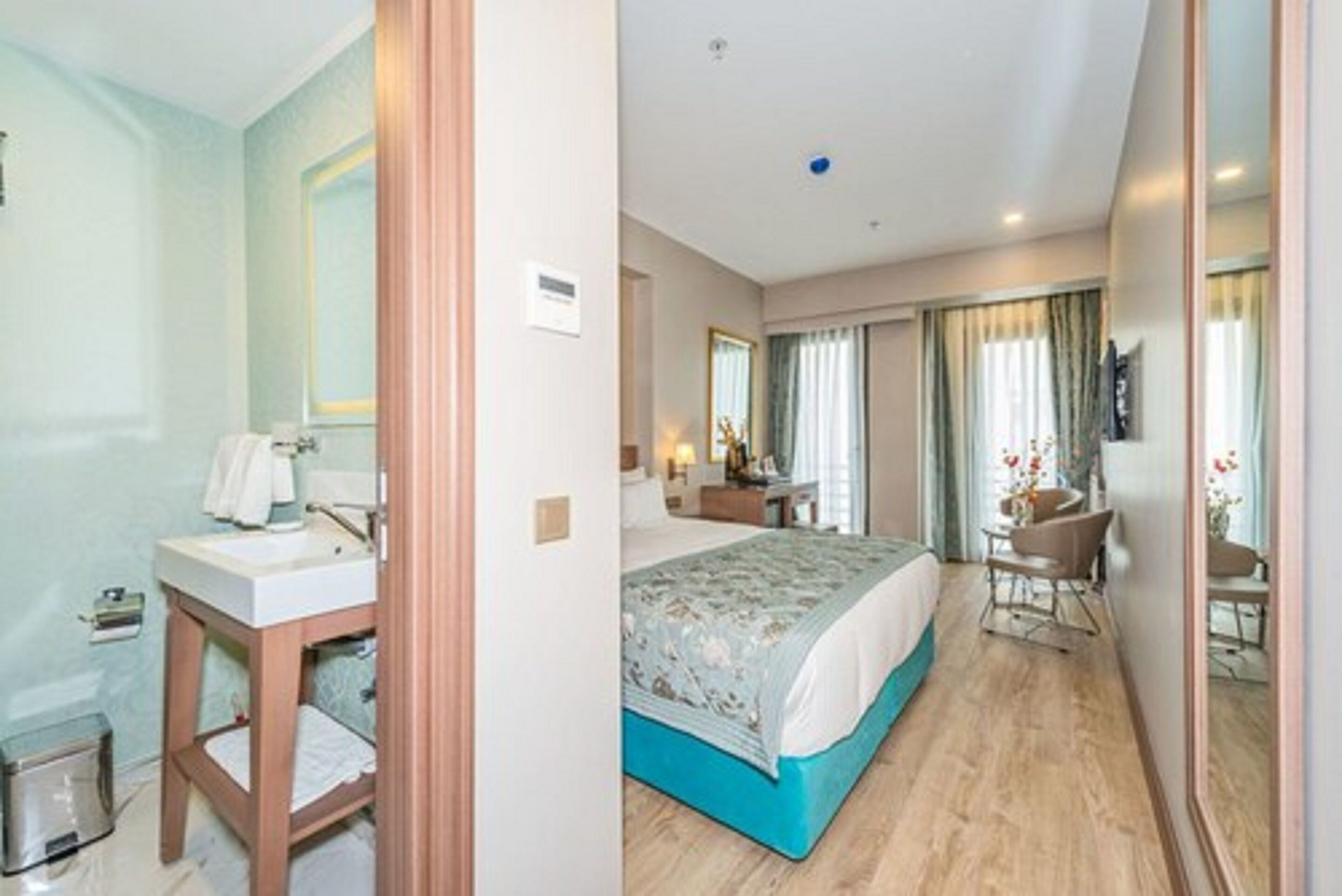 A hotel room with a bathroom, a bed, a desk, and a chair.
