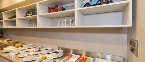 Un buffet garni de divers plats et une collection de voitures jouets exposée sur des étagères.