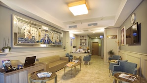 A hotel lobby with a reception desk, seating area, and a large decorative mirror. - Taximist Hotel (Istanbul)