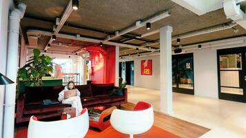 A modern interior with a red sofa, white chairs, and a large plant.