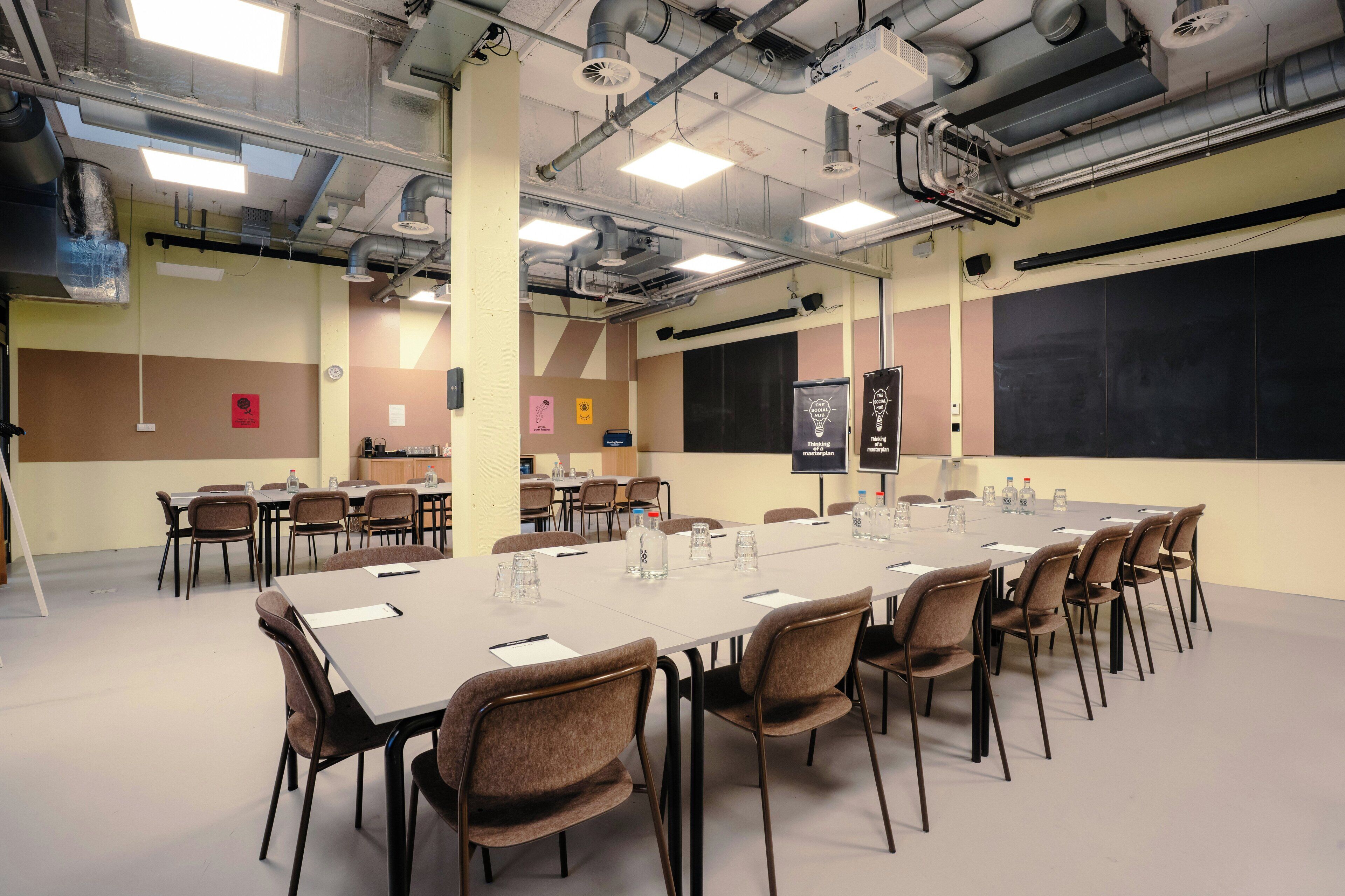 Ein Konferenzraum mit langem Tisch, Stühlen und einer Tafel.