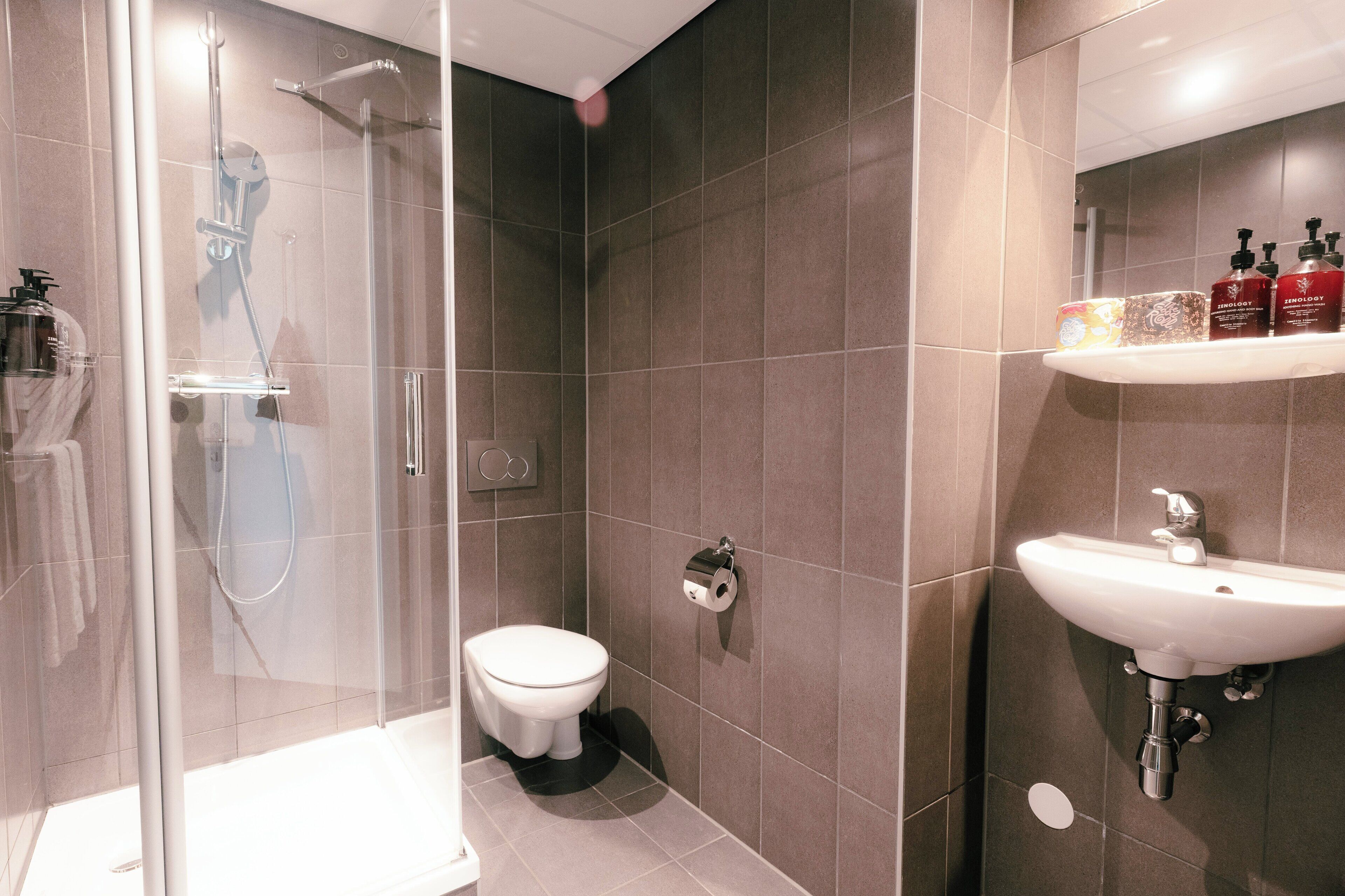 Une salle de bain moderne avec une douche à parois de verre, des toilettes et un lavabo équipé de produits de toilette.