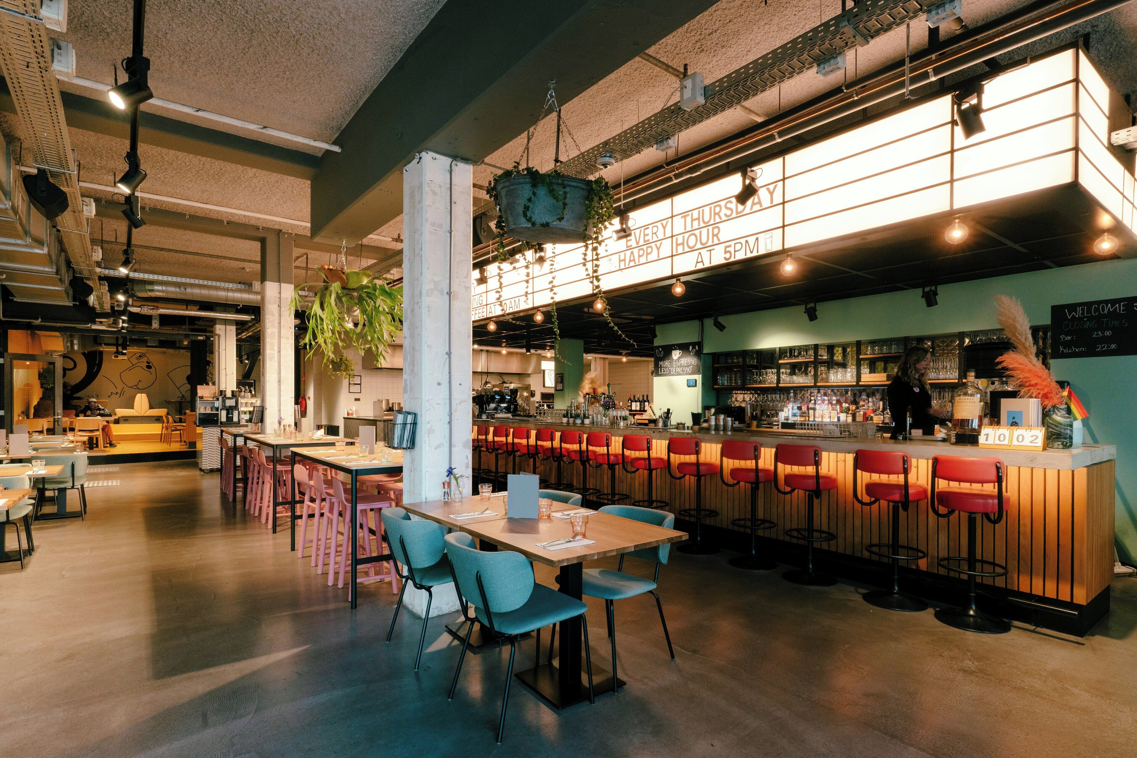 Uma área de bar moderna com assentos, balcão e plantas penduradas.
