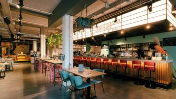 Uma área de bar moderna com assentos, balcão e plantas penduradas.