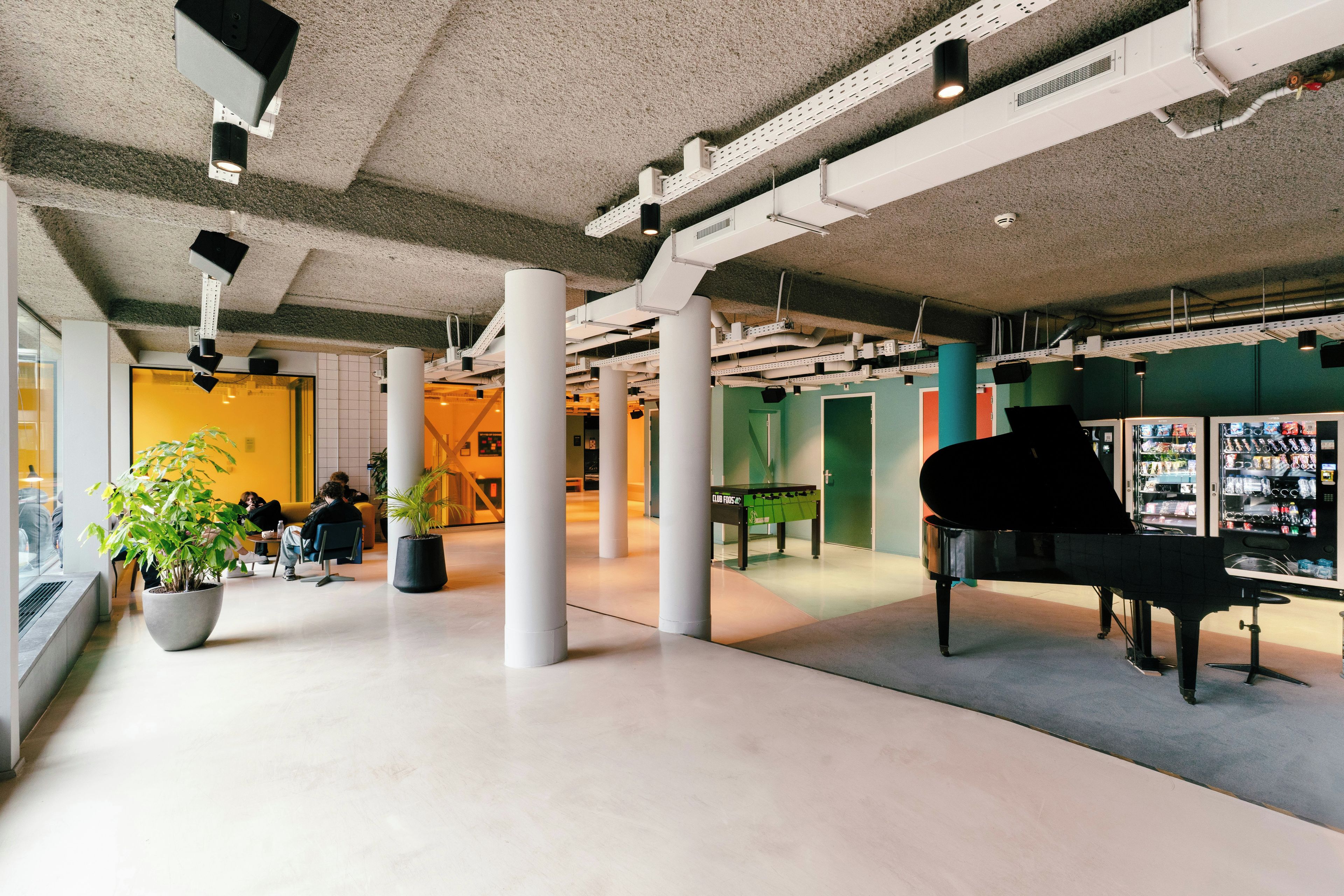 Un espacio interior amplio con un piano, asientos y una máquina expendedora.