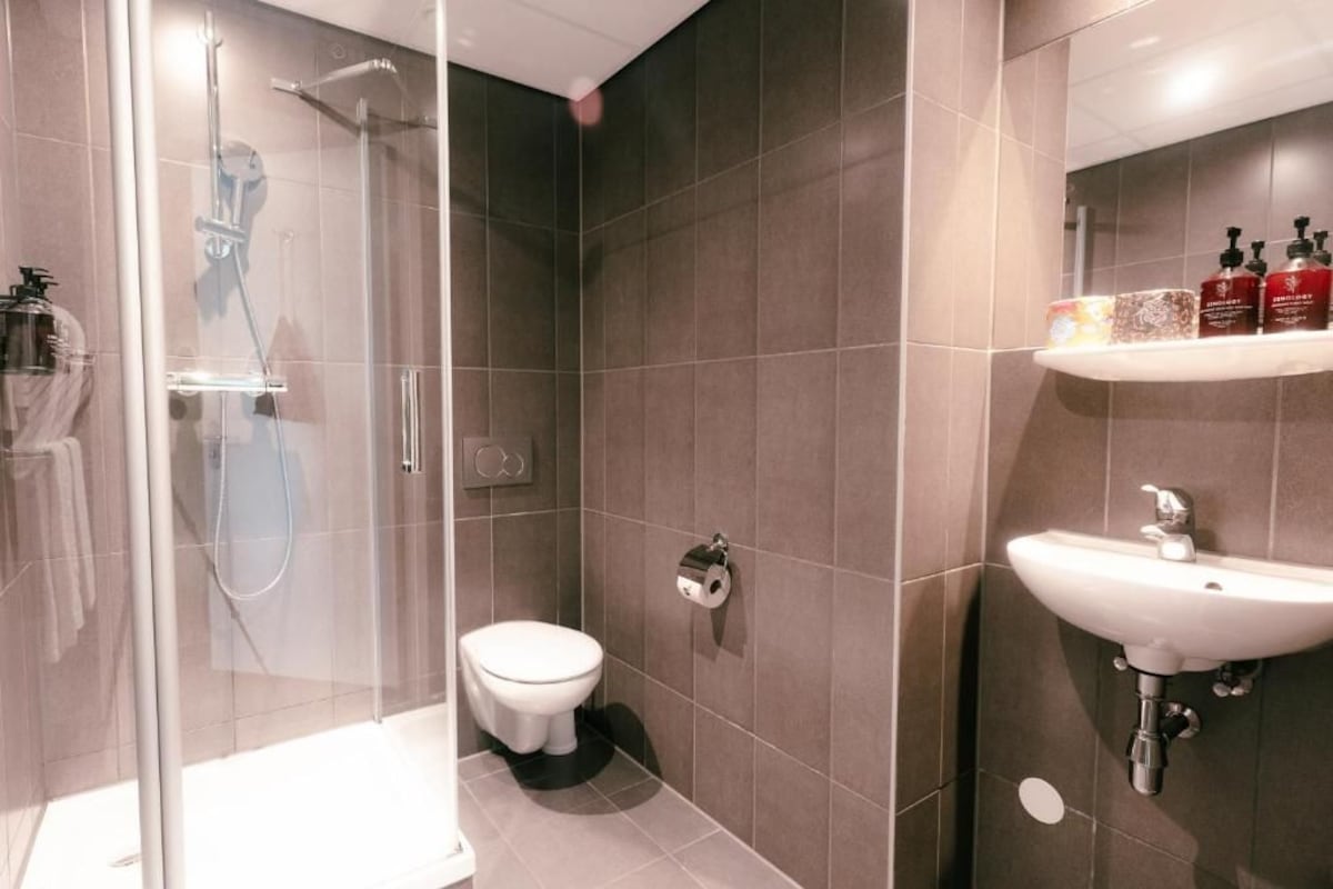 Une salle de bain moderne avec une douche à parois de verre, des toilettes et un lavabo équipé de produits de toilette.