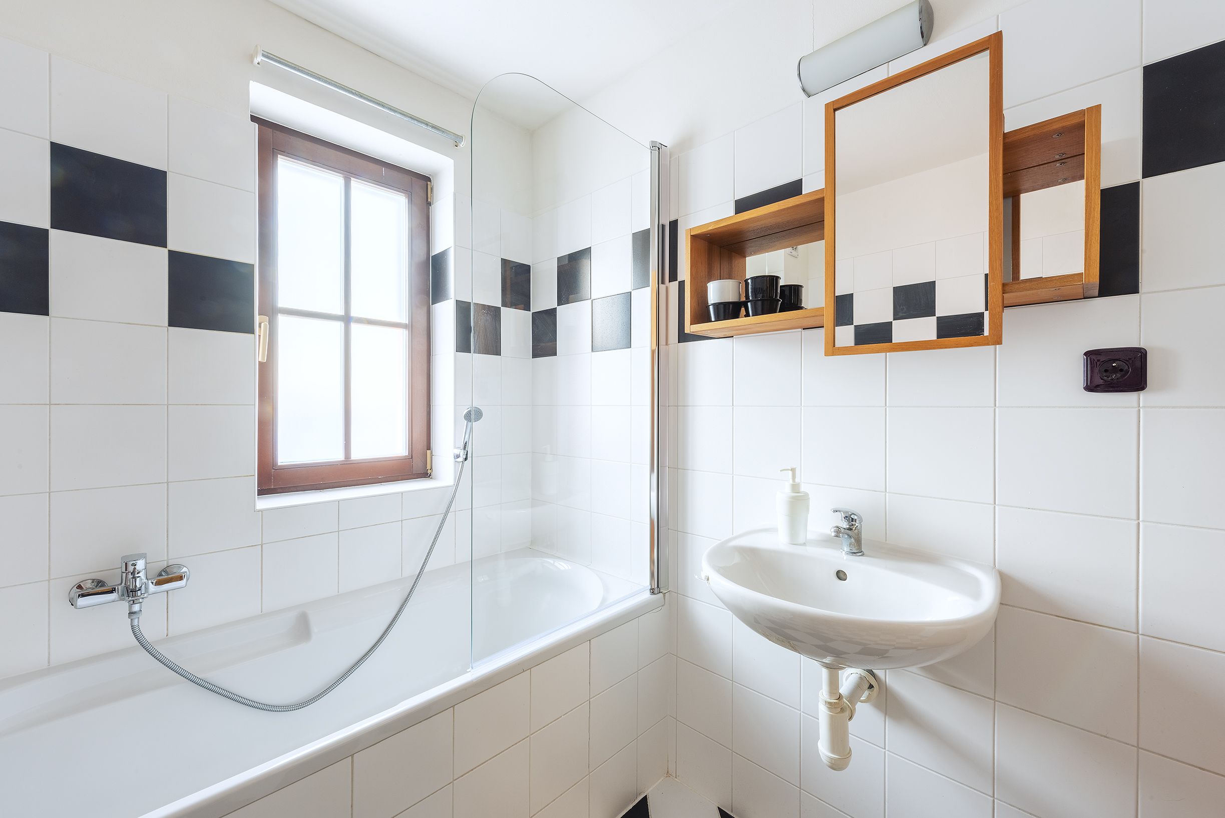 A bathroom with a bathtub, a shower, a sink, and a window.