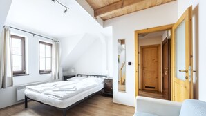 Une chambre à coucher avec un lit, un plancher en bois, une fenêtre et une porte.