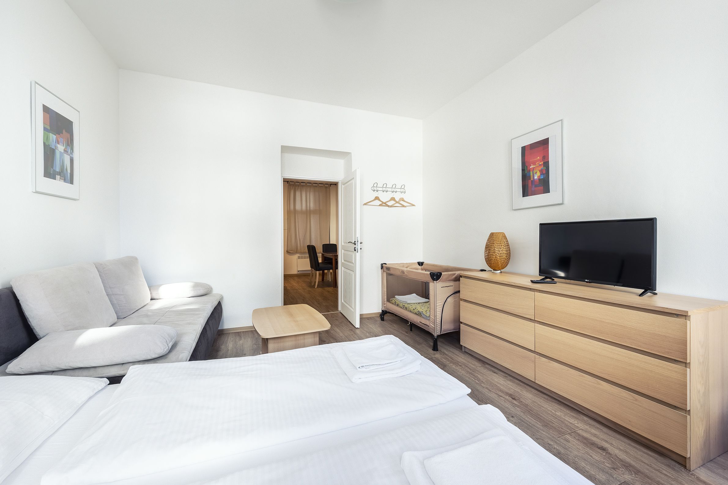 A modern hotel room with a bed, a desk, a TV, and a wardrobe.
