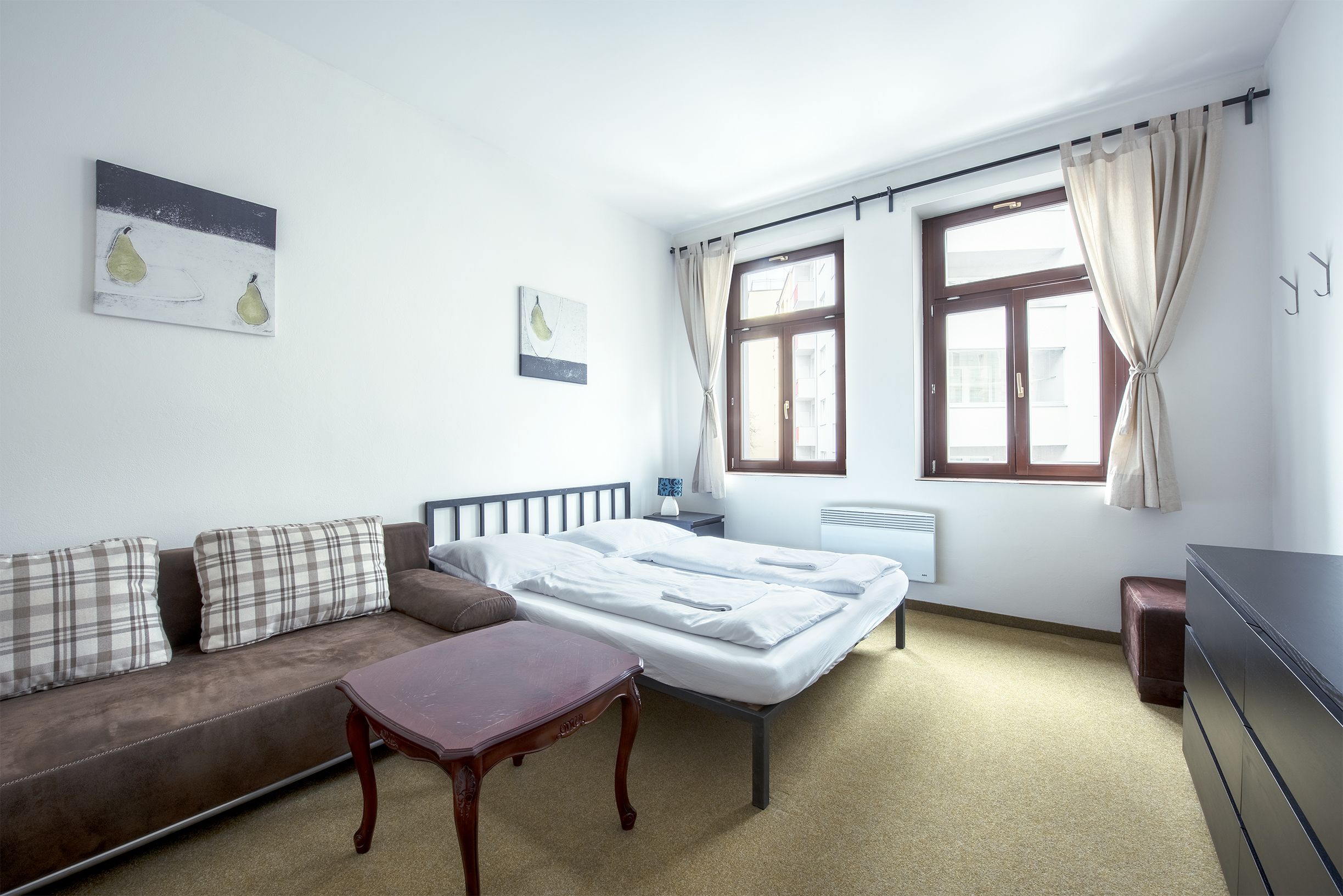 Un dormitorio con cama, sofá, mesita y cómoda.