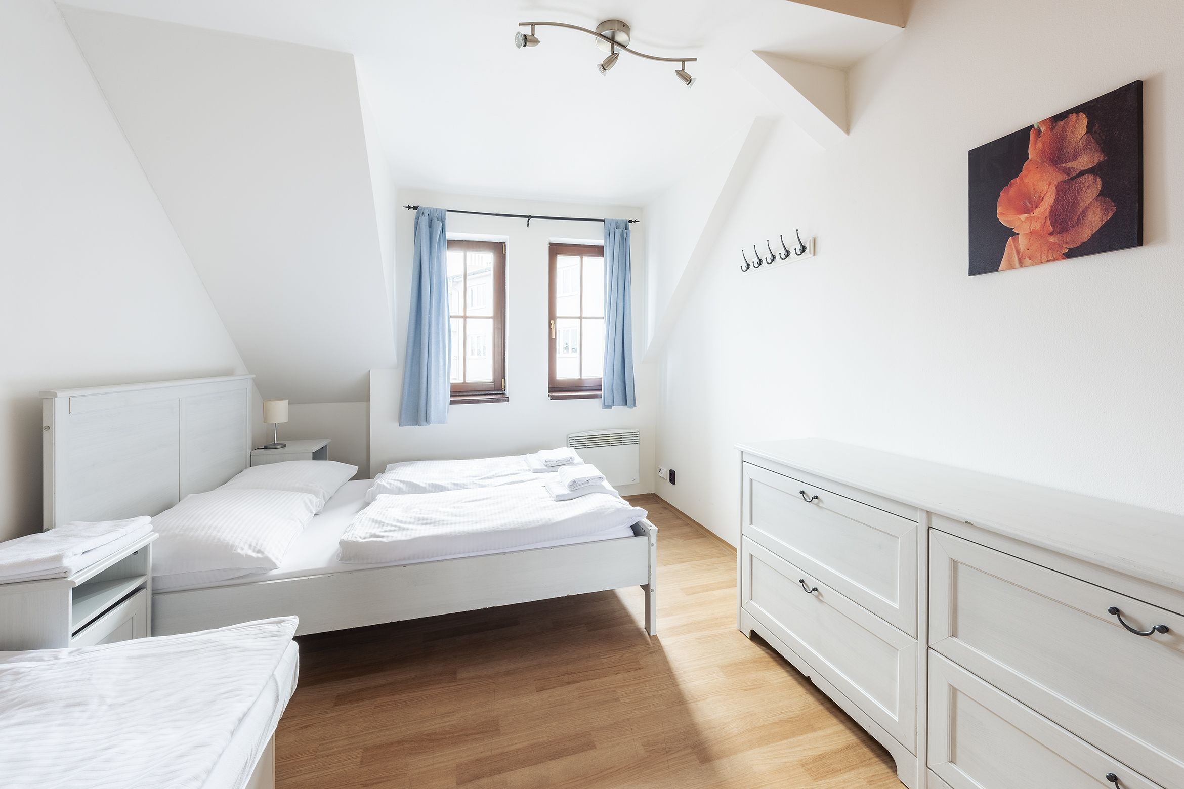 A bedroom with a bed, bedside tables, a dresser, and a window with curtains.