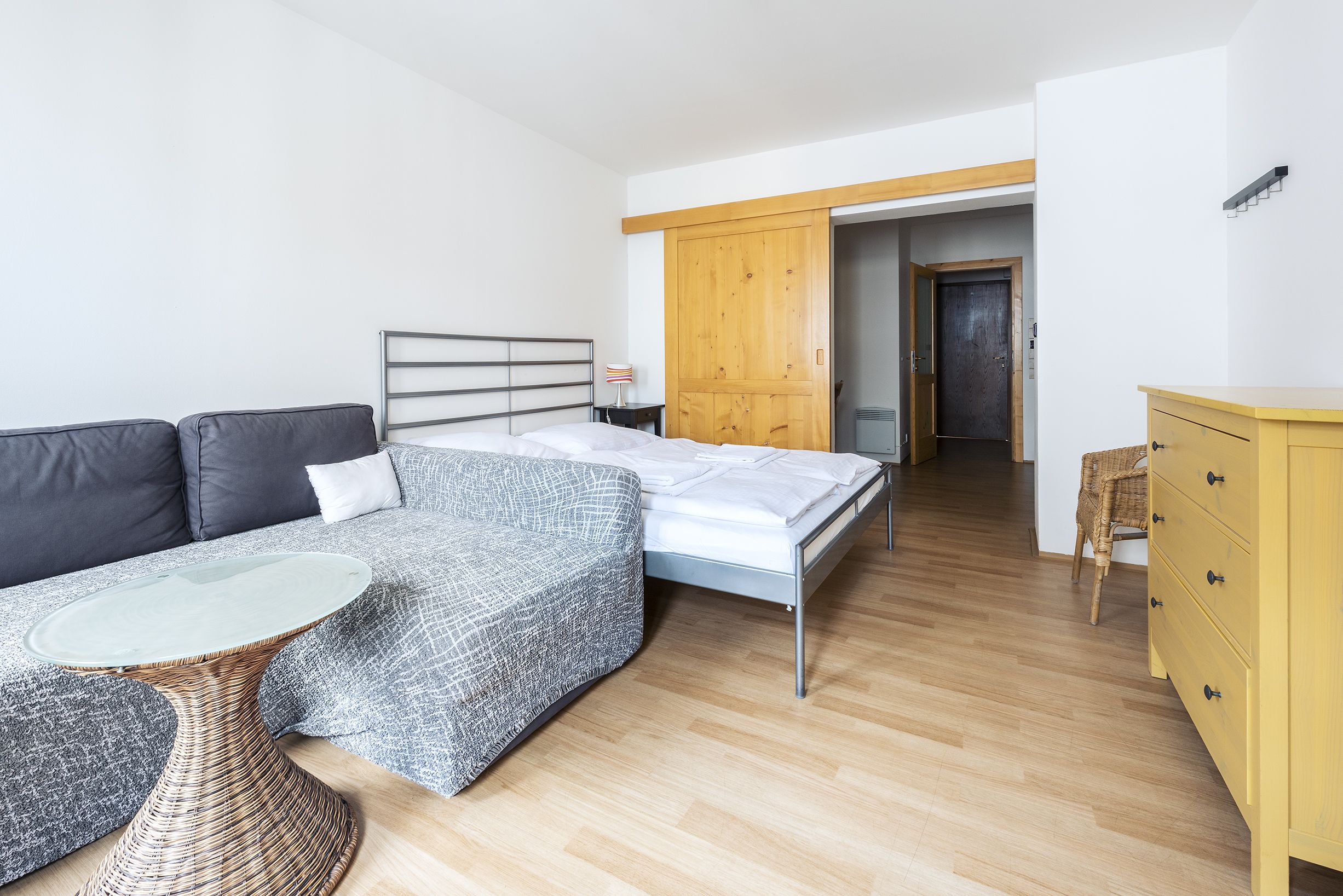 A modern bedroom with a bed, a sofa, a small table, and a wardrobe.