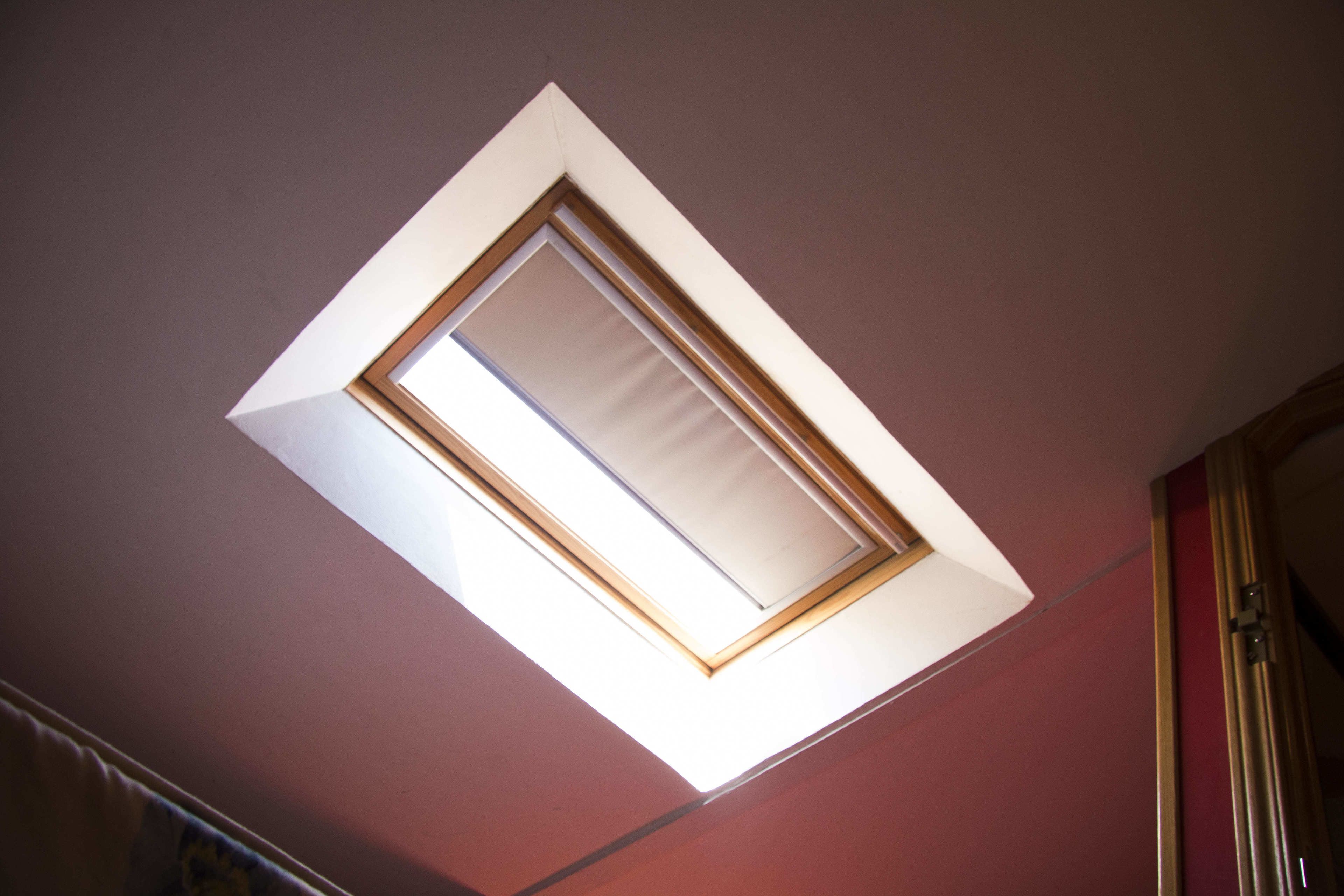 A skylight in a room with a red wall and a wooden door frame.