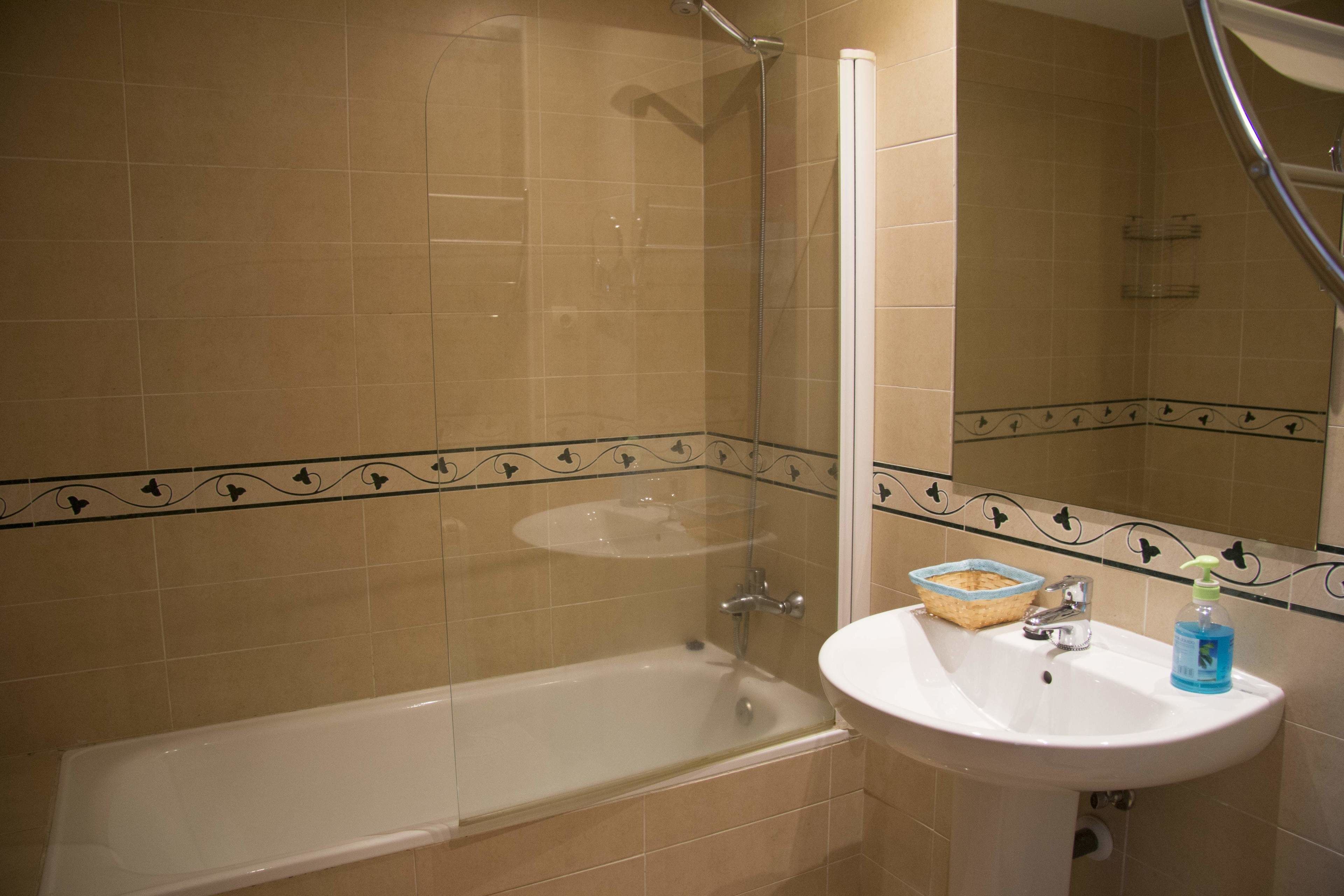 A bathroom with a bathtub, a sink, and a mirror.