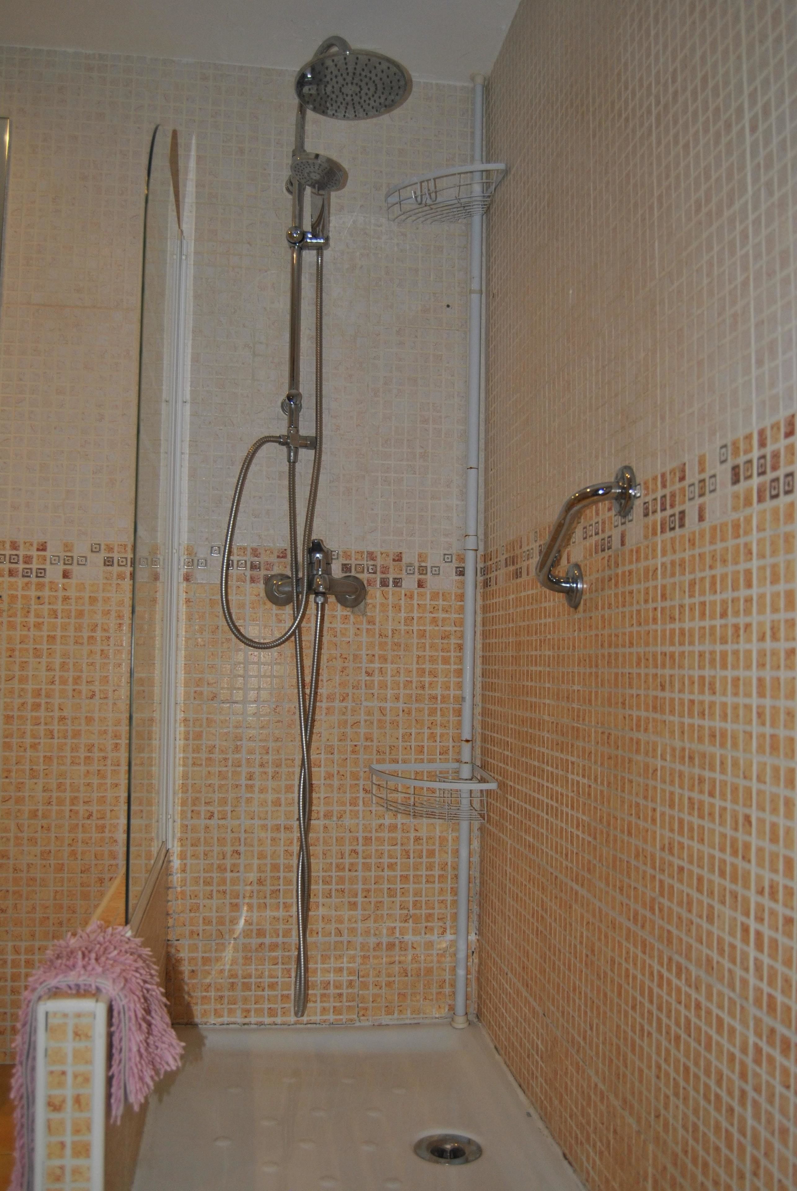 Un área de ducha con cabezal de ducha manual, cabezal de ducha de pared y cabezal de ducha manual con manguera.