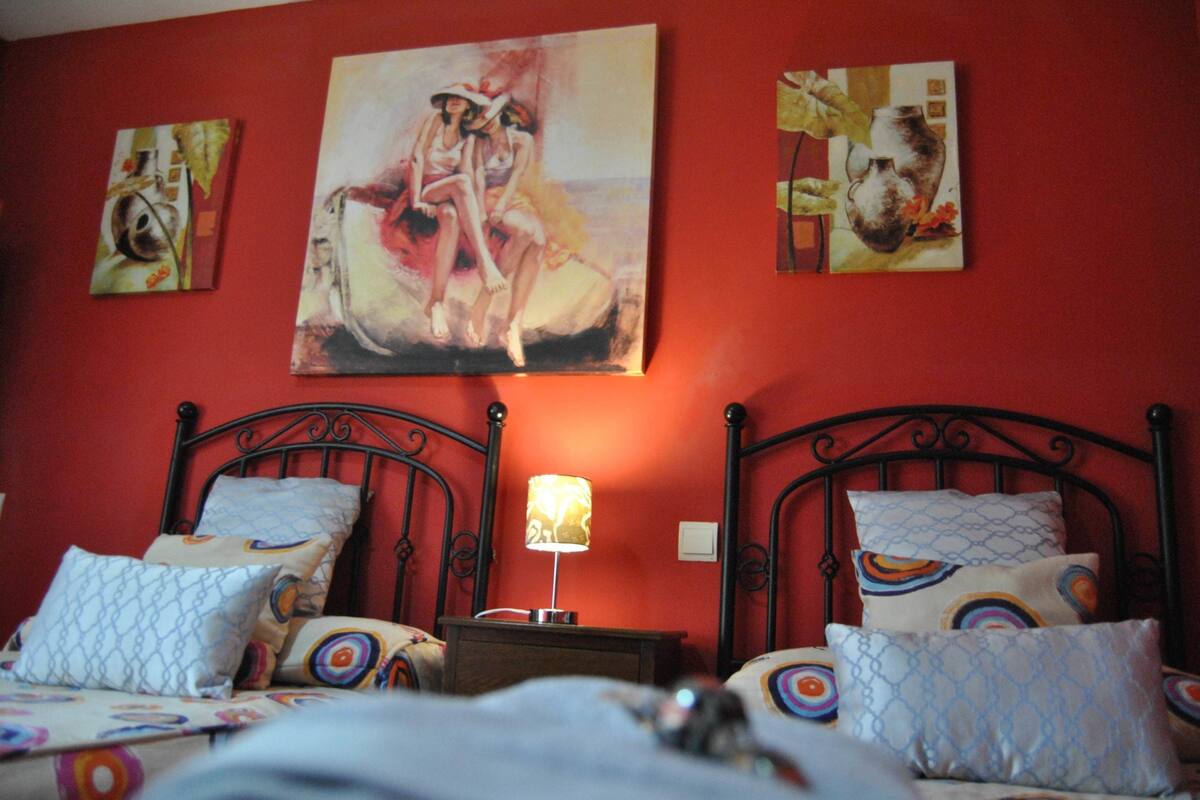 A bedroom with two beds, a nightstand, and wall art.