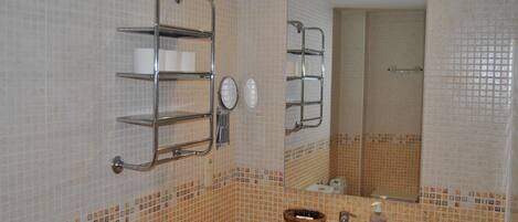 A bathroom with a sink, mirror, towel rack, and a shower area.