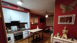 Una cocina compacta con comedor, lavadora, ventilador de techo y una estatua decorativa de Buda.