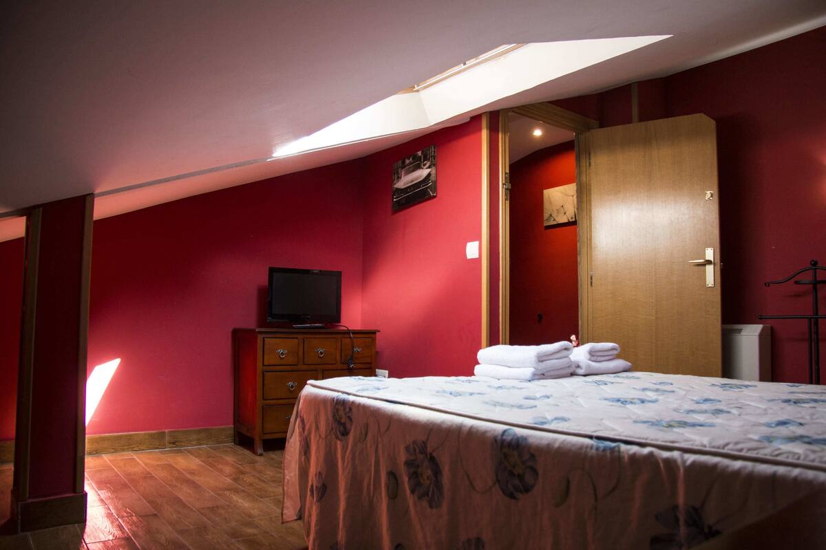 A bedroom with a bed, a dresser, a television, and a wardrobe.