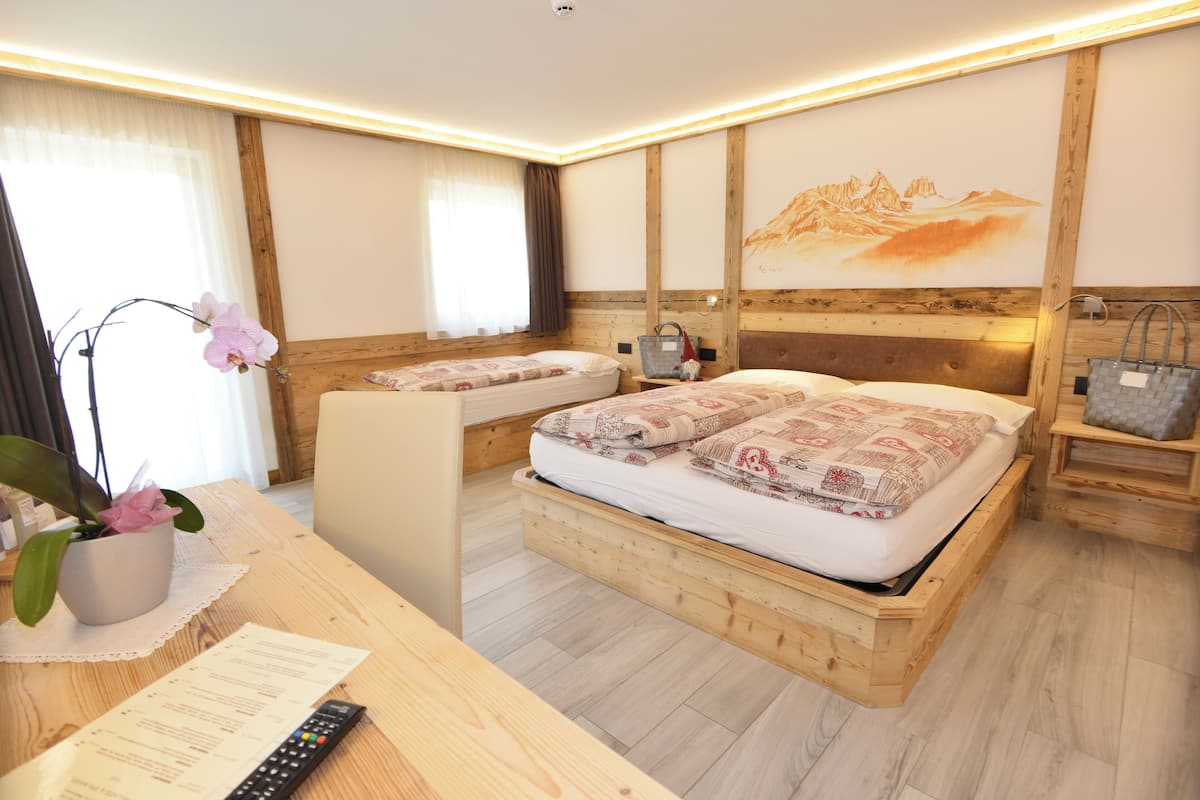 Une chambre d’hôtel avec un lit en bois, un bureau doté d’une télécommande et une orchidée en pot.
