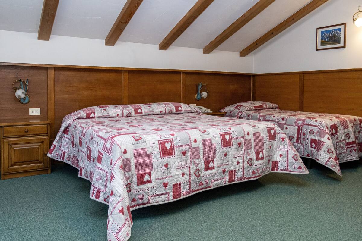 Une chambre avec deux lits, une tête de lit en bois et une moquette verte.