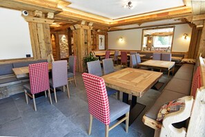 A restaurant with wooden interior, checkered tablecloths, and a stone wall. - Wellness Hotel Dolomia (Soraga)