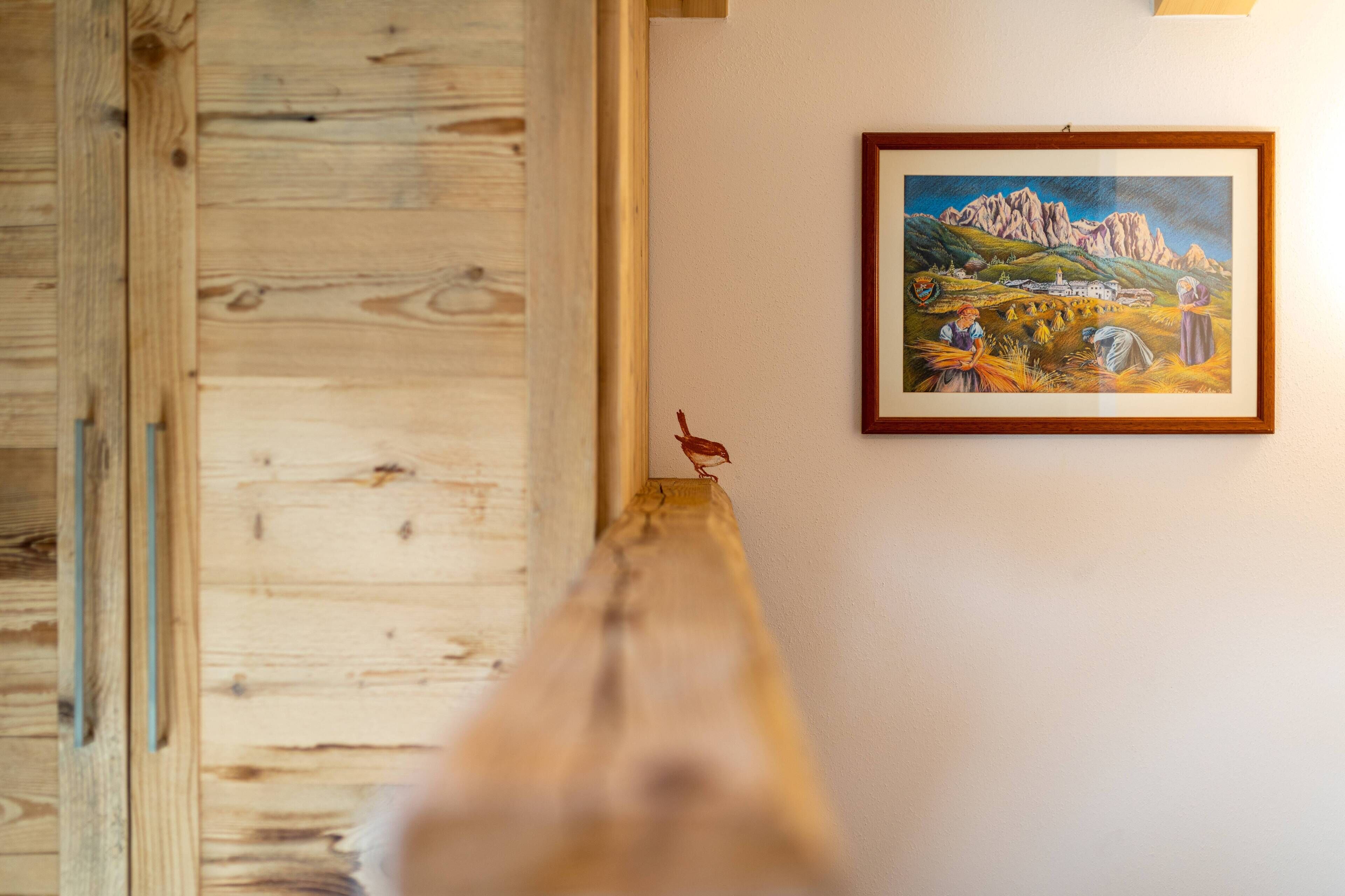 A wooden bench in a room with a framed painting on the wall.