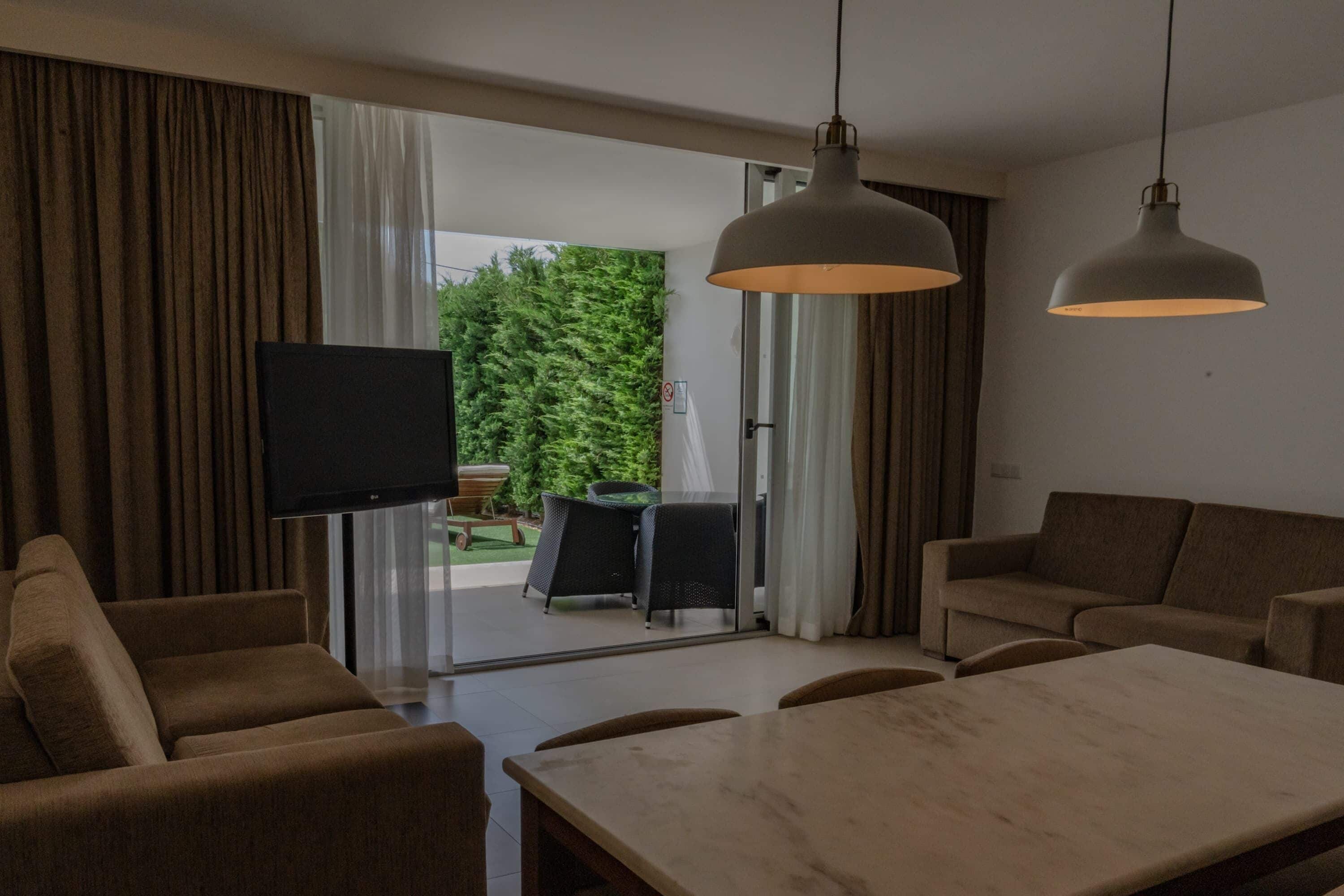 A modern living room with a sofa, a dining table, and two pendant lights.