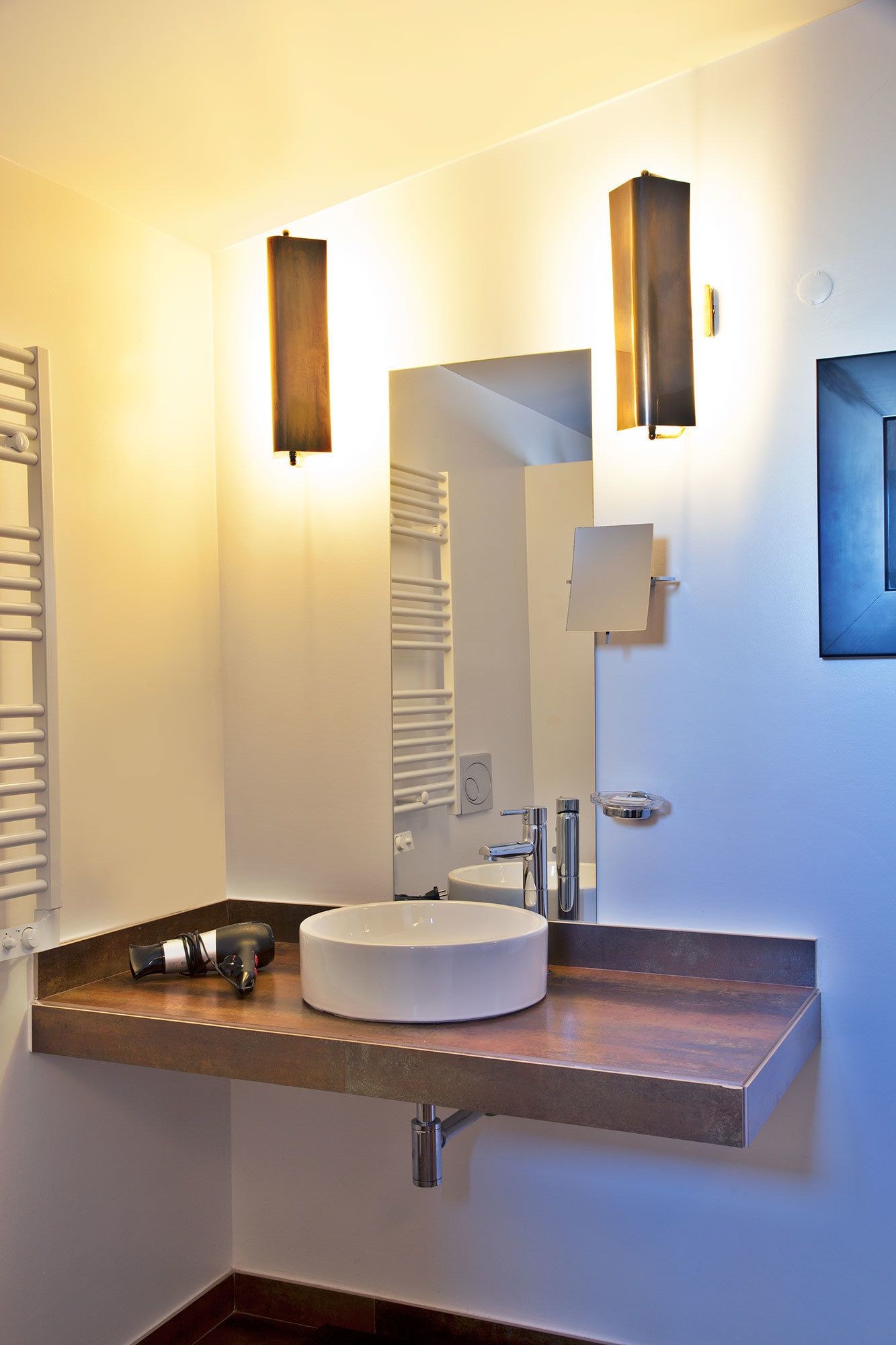 Moderni kylpyhuone, jossa on pyöreä pesuallas, pyyhekoukku ja peili.