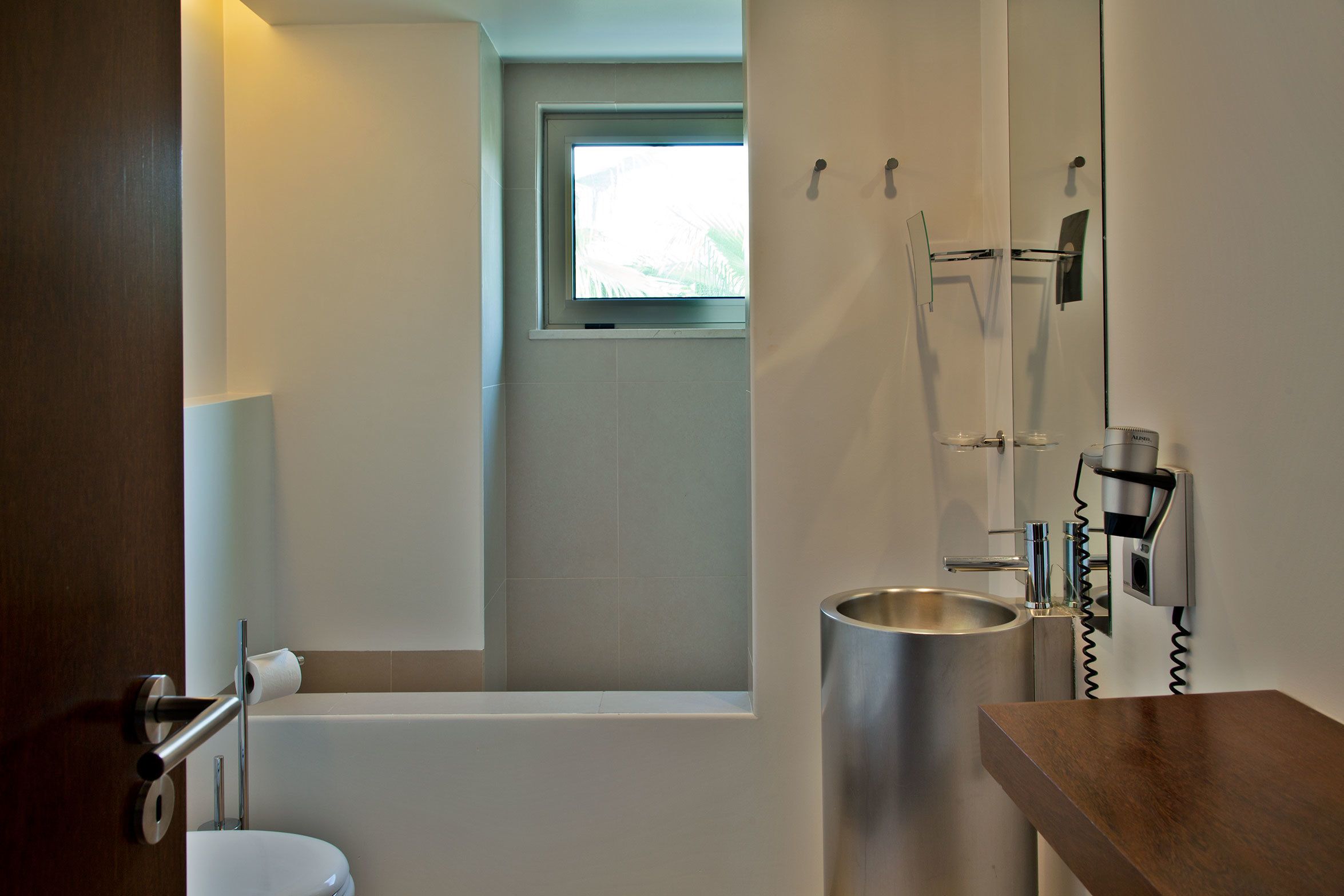 A bathroom with a toilet, a sink, a mirror, and a shower.