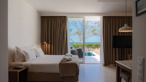 A hotel room with a bed, a desk, a TV, and a view of the ocean. - São Rafael Holidays (Albufeira)