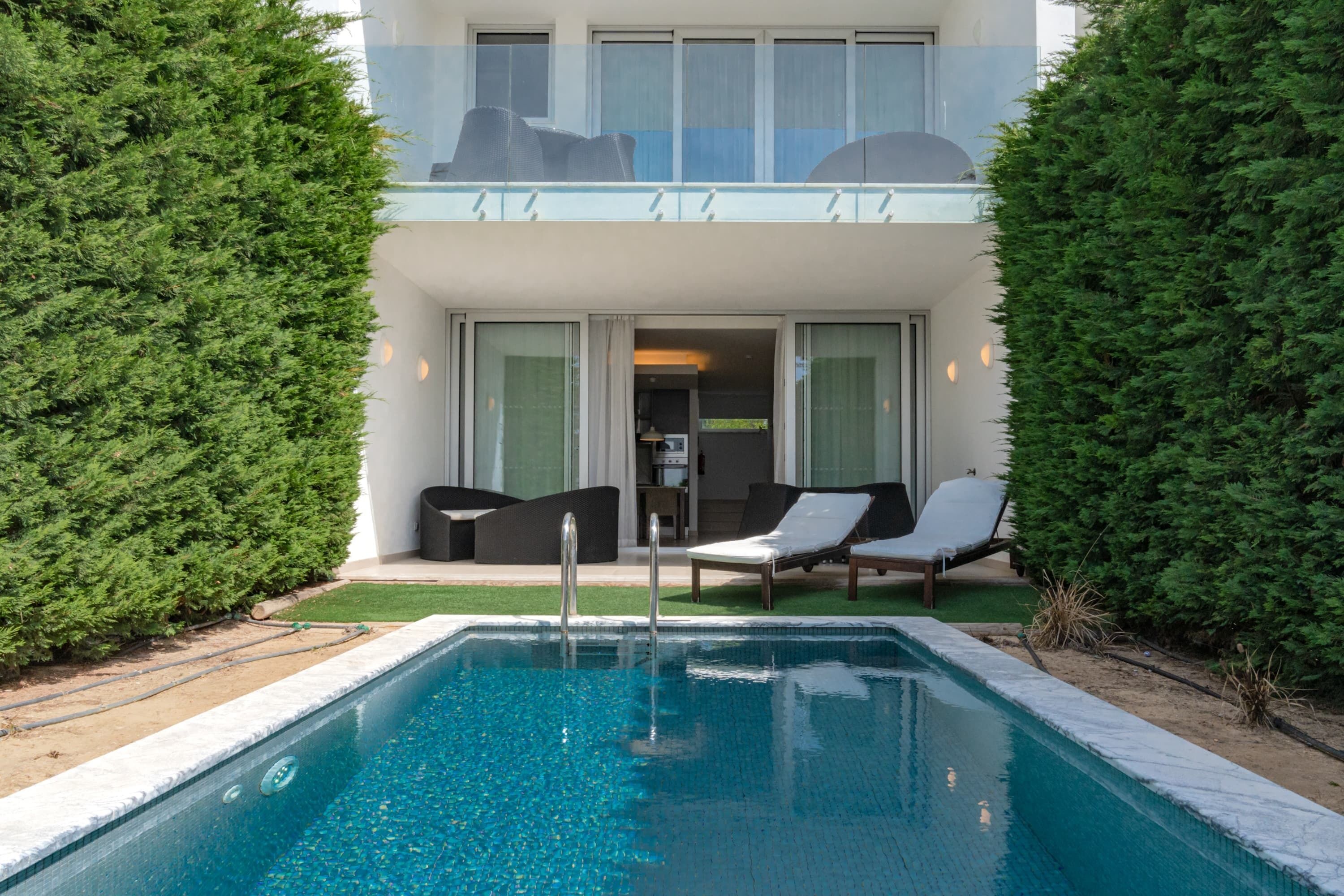 Una piscina al aire libre, sillones reclinables de piscina