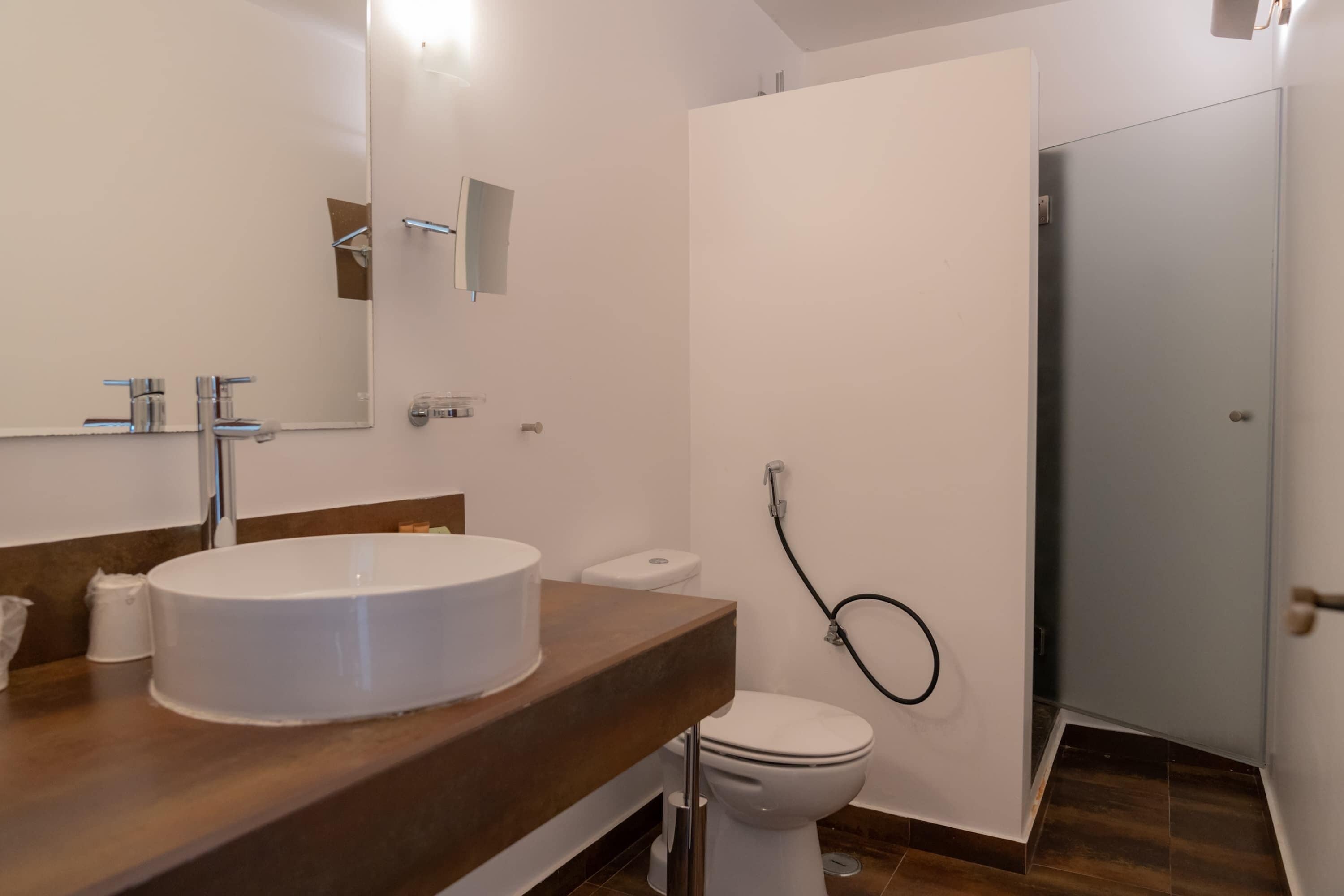 Een moderne badkamer met een groot wit wastafel, een spiegel, een toilet en een douchehoek.
