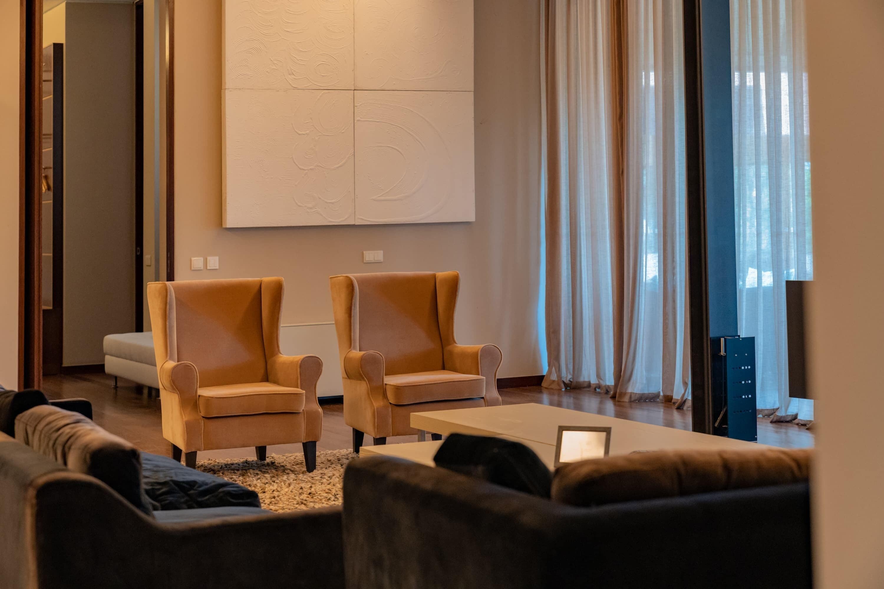 Uma sala de estar moderna com dois poltronas, um sofá e uma mesa de centro.