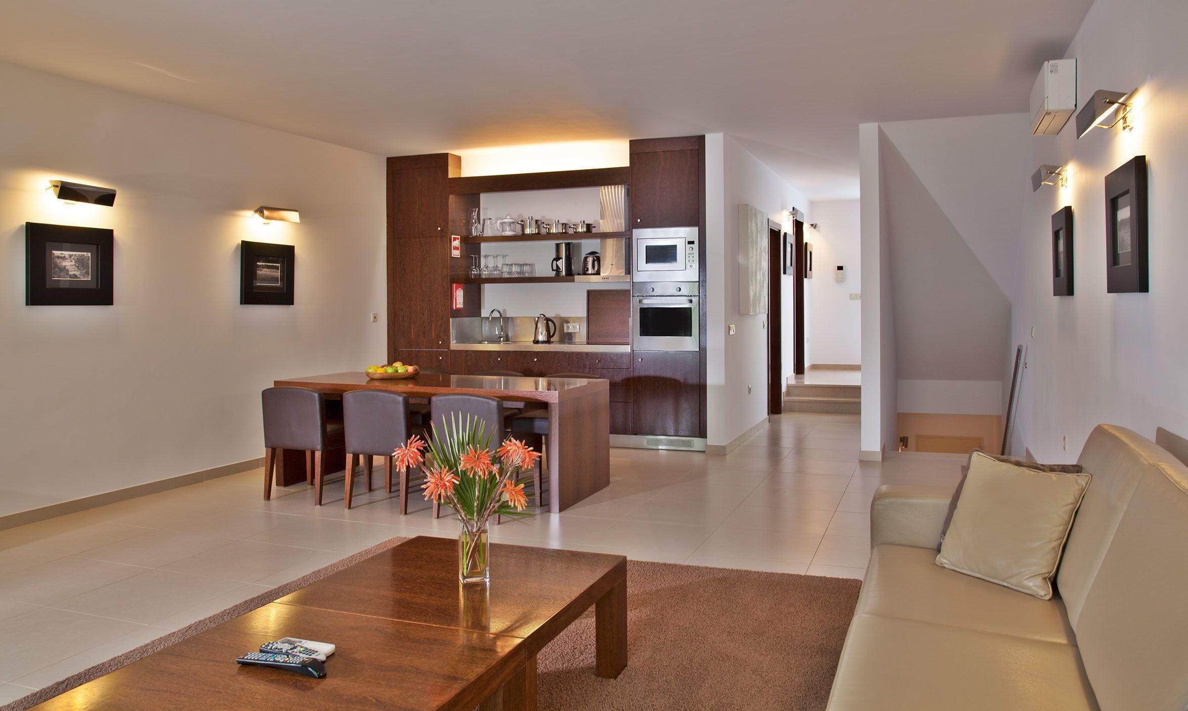 Un salon moderne avec une table basse en bois, un canapé et un coin cuisine comprenant une table à manger et des chaises.